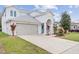 Charming two-story home with a well-manicured lawn, arched entrance, and attached two-car garage at 4104 Warwick Hills Dr, Wesley Chapel, FL 33543