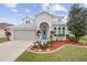 Charming two-story home with a well-manicured lawn, arched entrance, and attached two-car garage at 4104 Warwick Hills Dr, Wesley Chapel, FL 33543