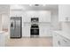 Bright kitchen featuring white cabinets, stainless steel appliances, and ceramic tile flooring at 4104 Warwick Hills Dr, Wesley Chapel, FL 33543