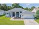 Single-story home with gray roof, attached garage, and a lush green lawn at 10328 Henderson St, Spring Hill, FL 34608
