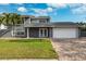 Two-story house with gray exterior, white garage door, and brick paver driveway at 8201 Kirkwood Dr, Tampa, FL 33634