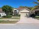 Tan one-story house with a two-car garage and landscaped yard at 9305 Haas Dr, Hudson, FL 34669