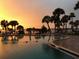 Relaxing community pool with palm trees and sunset view at 100 Bluff View Dr # 415A, Belleair Bluffs, FL 33770