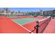 Community tennis courts with red and green surfaces, surrounded by a fence and lush palm trees at 273 Madeira Cir, Tierra Verde, FL 33715