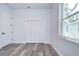 Simple bedroom with wood-look floors, white louvered doors, and a window at 3125 Downing St, Clearwater, FL 33759