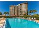 Beautiful pool area with lounge chairs, lush landscaping, and a view of the high rise building at 736 Island Way # 606, Clearwater Beach, FL 33767