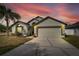 Charming single-story home boasts a two-car garage, lovely landscaping, and a beautiful sunset backdrop at 31935 Brookstone Dr, Wesley Chapel, FL 33545