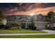 Two-story house with a green exterior, three-car garage, and landscaping at 26888 Fiddlewood Loop, Wesley Chapel, FL 33544