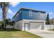 Two-story home with a blue exterior, white garage, and a landscaped yard at 3276 Sea Grape Dr, Hernando Beach, FL 34607