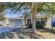 One-story house with gray garage door, brown door, and large tree in the front yard at 445 Alpine Thistle Dr, Brooksville, FL 34604