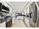 Galley kitchen with stainless steel appliances, white cabinets, and black countertops at 5474 Kemkerry Rd, Wesley Chapel, FL 33543