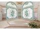Bright bathroom featuring a soaking tub under stained glass windows and surrounded by mirrors at 1388 Brightwaters Ne Blvd, St Petersburg, FL 33704