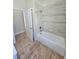 Bright bathroom featuring tile tub surround, wood look tile floors, and white door at 295 Woodstream Way, Spring Hill, FL 34608