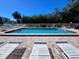 Community pool area with lounge chairs, tables, and seating surrounded by landscaping at 322 Windrush Blvd # 2, Indian Rocks Beach, FL 33785