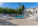 Enjoy this community pool area surrounded by comfortable seating, a brick patio, and lush landscaping at 322 Windrush Blvd # 2, Indian Rocks Beach, FL 33785
