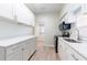 Bright kitchen featuring white cabinets, countertops, stainless steel appliances, and wood-look flooring at 3424 Queensboro S Ave, St Petersburg, FL 33711