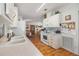 White kitchen with appliances, wood flooring, and view of dining area at 37340 Neukom Ave, Zephyrhills, FL 33541