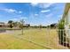 Expansive backyard with white fence and serene water views under a blue sky with puffy white clouds at 1074 Signet Dr, Apollo Beach, FL 33572