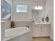 A soaking tub sits next to a white vanity in this well-lit and decorated bathroom space at 1074 Signet Dr, Apollo Beach, FL 33572