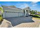 Beautifully designed single-story home boasts a three-car garage, brick driveway, and lush landscaping at 1074 Signet Dr, Apollo Beach, FL 33572