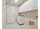 Bright laundry room with white cabinets, utility sink, and built-in shelving at 11609 Weaver Park Ct, Trinity, FL 34655