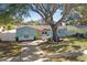 Charming light blue home with a yellow door and large tree at 2209 Gladys St, Largo, FL 33774