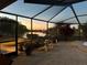 An evening view of the screened-in back patio featuring a spa, brick pavers, and an outdoor seating area at 2337 Platinum Dr, Sun City Center, FL 33573