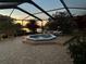 Evening view of the screened-in back patio with tiled spa, brick pavers, and a scenic lake view at 2337 Platinum Dr, Sun City Center, FL 33573