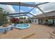 Screened-in back patio featuring brick pavers, potted plants, spa, and an outdoor dining area at 2337 Platinum Dr, Sun City Center, FL 33573