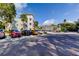 View of the condo building with the parking lot that features various vehicles and trees at 2460 Persian Dr # 26, Clearwater, FL 33763