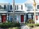 Charming townhome with vibrant red door, lush landscaping and tropical palm trees, offers inviting curb appeal at 262 Countryside Key Blvd, Oldsmar, FL 34677