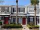 Charming townhome with vibrant red door, lush landscaping and tropical palm trees, offers inviting curb appeal at 262 Countryside Key Blvd, Oldsmar, FL 34677