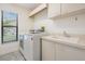 Well-lit laundry room with modern washer and dryer, ample counter space, and a window at 3360 Hickorywood Way, Tarpon Springs, FL 34688