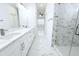 Bathroom with marble-look tile, dual sinks with white cabinets and drawers, and a glass enclosed shower at 408 E Hanlon St, Tampa, FL 33604