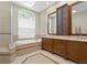 Luxurious bathroom with a soaking tub beneath an arched window and a double vanity with custom cabinetry at 10106 Radcliffe Dr, Tampa, FL 33626