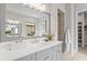 Contemporary bathroom with a large mirror, dual sinks, and a view of the tiled shower, combining style and functionality at 10639 Ruffino Ct, Trinity, FL 34655