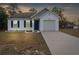 Newly built home with gray and white siding, a two-car garage, and a landscaped yard at 13004 Marsh Hawk Rd, Weeki Wachee, FL 34614