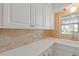 Kitchen counter with white cabinets, brick backsplash, and a window at 3717 46Th S Ave # 6, St Petersburg, FL 33711