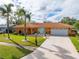 Orange house with a large yard, palm trees, and a long driveway at 6888 121St N St, Seminole, FL 33772