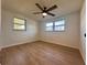 Bright bedroom features hardwood floors, two windows, and ceiling fan with lights at 7521 Bougenville Dr, Port Richey, FL 34668