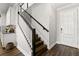 Elegant staircase with wood steps, black railing, and a white door leading to the entryway at 1003 Starboard Ct, Oldsmar, FL 34677