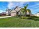 Tan one-story house with a two-car garage and landscaped yard at 7963 Sail Clover Ln, Zephyrhills, FL 33540