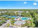 Aerial view of the community pool and tennis courts with lush landscaping and blue skies at 9418 W Park Village Dr # 105, Tampa, FL 33626