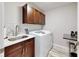 Convenient laundry room featuring a front-loading washer, sink, cabinets, and folding counter at 1957 Whitney Oaks Blvd, Clearwater, FL 33760