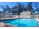 Community pool is surrounded by a white picket fence and mature landscaping at 1957 Whitney Oaks Blvd, Clearwater, FL 33760