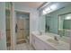 A well-lit bathroom with a double sink vanity, white tile flooring, and a glass-enclosed walk-in shower at 201 Silver Lake Dr # 204, Venice, FL 34292