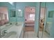 Bright bathroom with double sinks, white tile, and a view to the bedroom with ceiling fan and balcony access at 201 Silver Lake Dr # 204, Venice, FL 34292