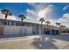 Multi-unit exterior featuring covered parking, storage, palm trees, and a sunny sky at 201 Silver Lake Dr # 204, Venice, FL 34292