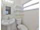 Compact bathroom with a pedestal sink, toilet, window, and floating shelves at 4116 Ohio Ave, Tampa, FL 33616
