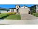 One-story house with tan siding, stone accents, and a two-car garage at 7122 Heron Walk Ln, Wesley Chapel, FL 33545